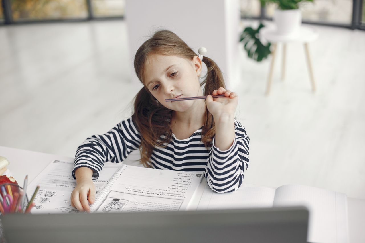 Crafting Captivating Headlines: Your awesome post title goes here A young girl thoughtfully doing her homework at a desk in a bright, cozy home interior.