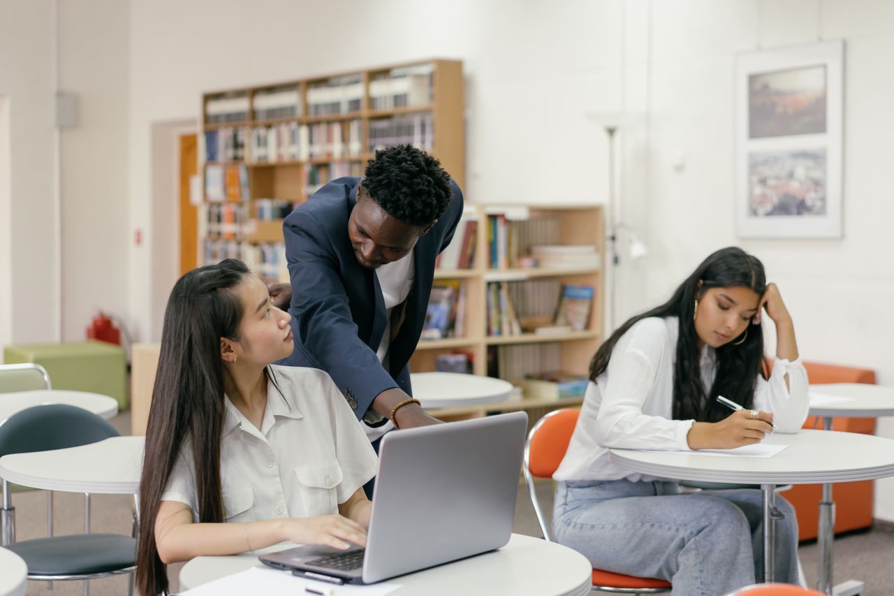 Services Students receiving guidance from a teacher in a well-equipped classroom.